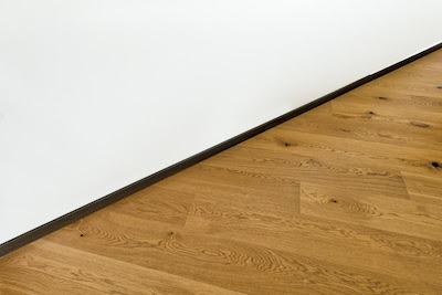 light brown wooden floorboards against white wall