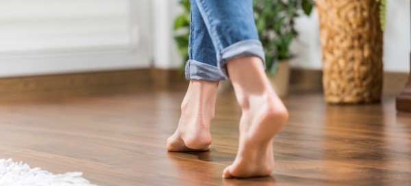 female walking barefoot on new hardwood floor in home